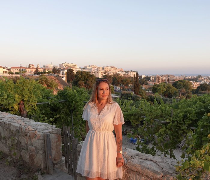 jana-schumacher-lächelt-in-weißem-kleid-bei-sonnenuntergang-mit-aussicht-auf-zypern